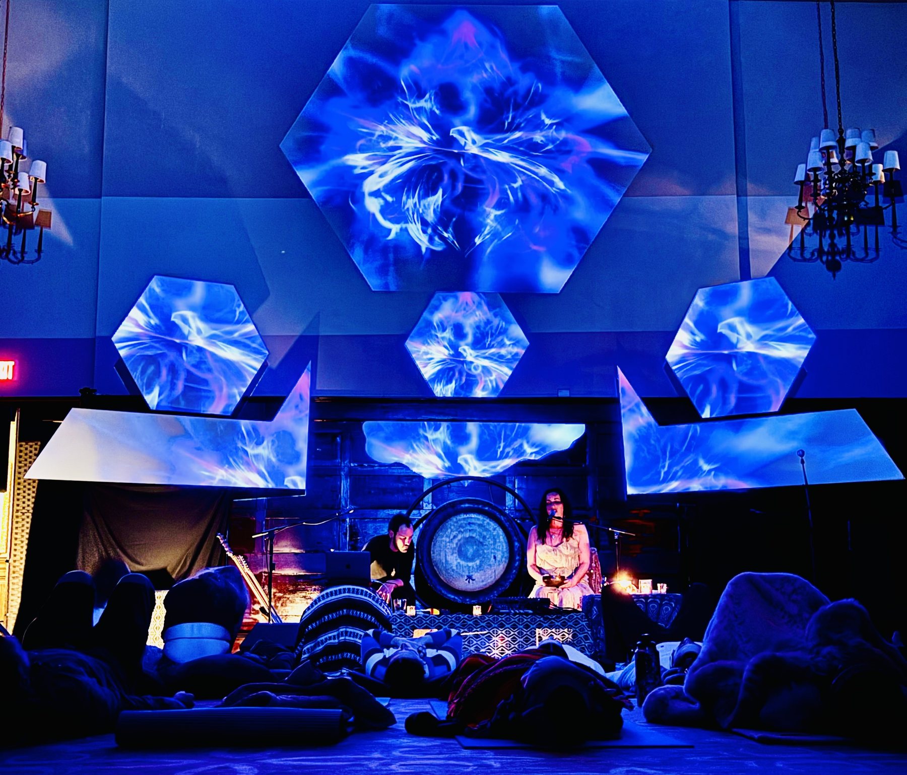 Sariah and Taylor perform beneath hexagon projections as the audience rests on the floor at the City Club of Baton Rouge
