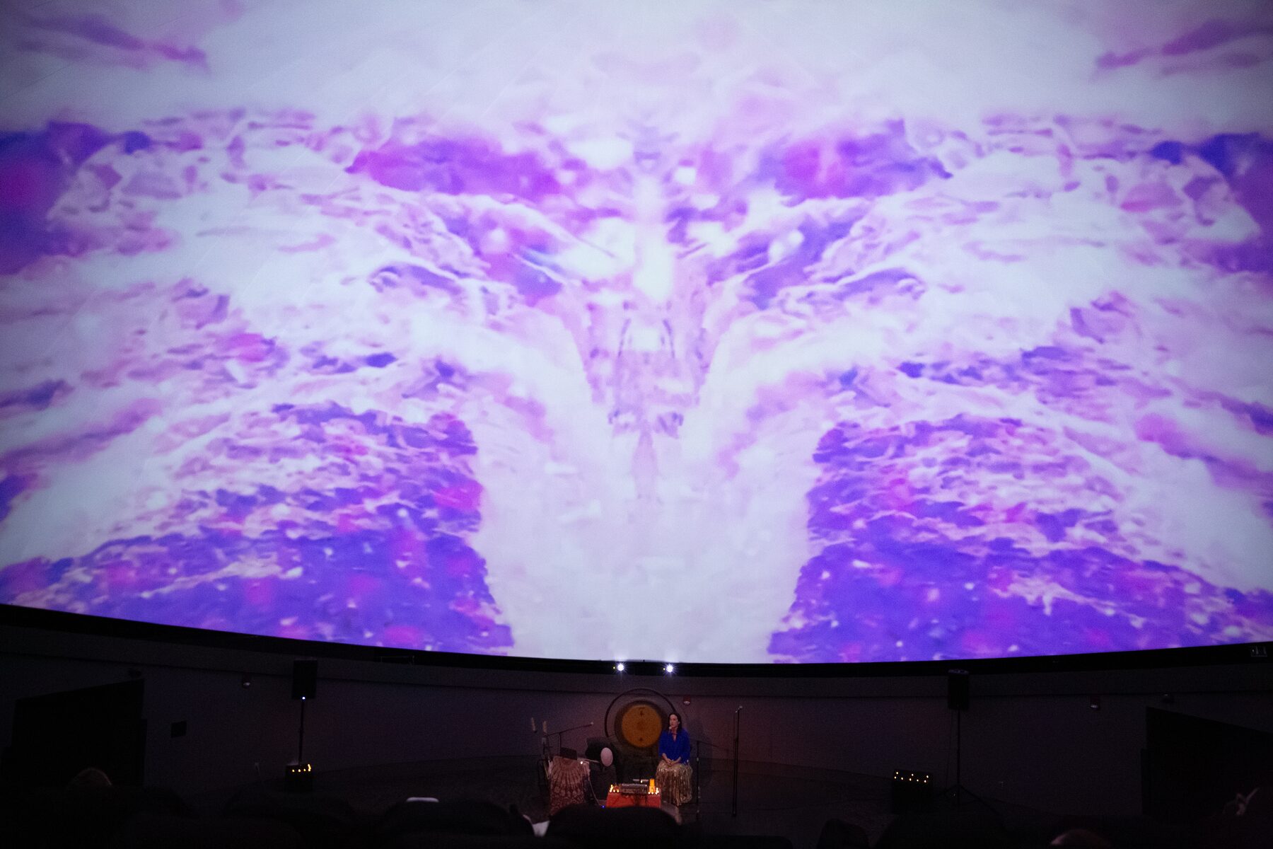 Lavender clouds mirrored into a symmetrical canyon of light above the stage
