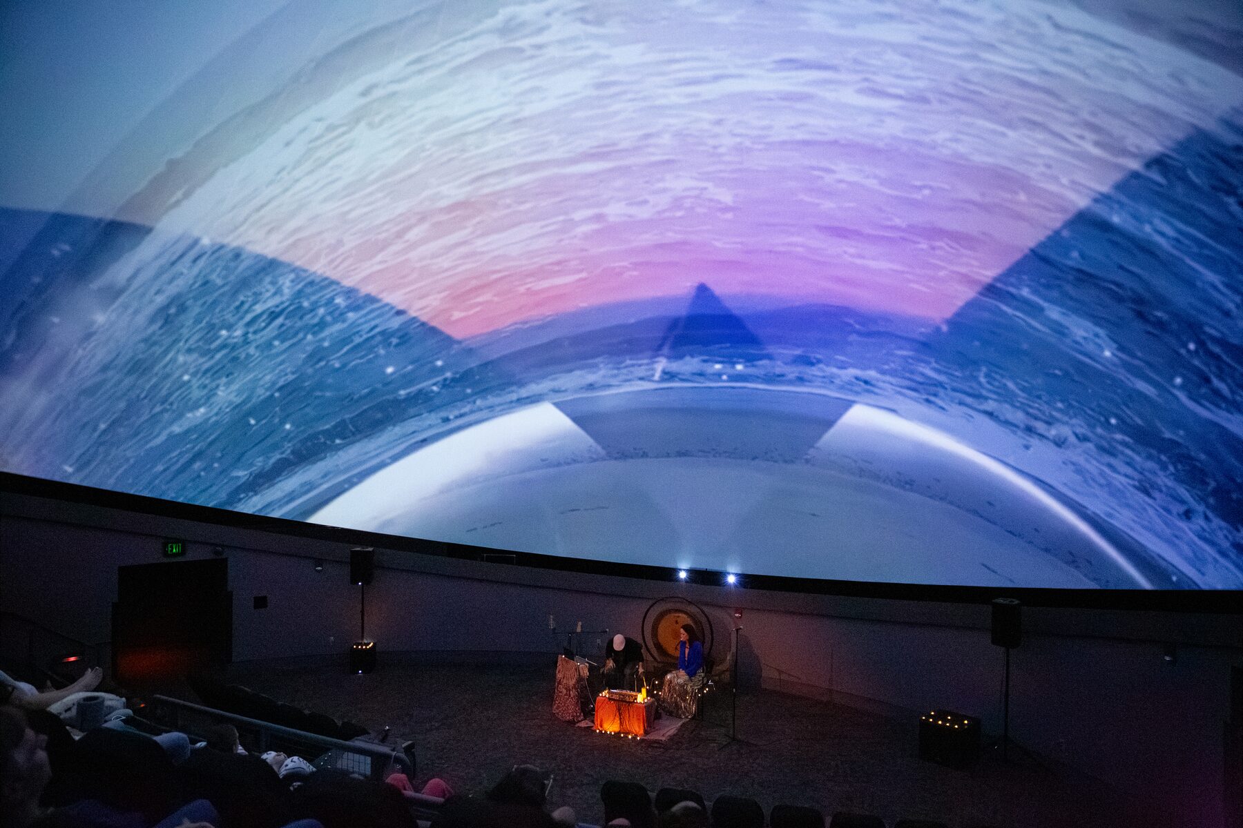 Sacred geometry lines web across a starfield on the dome as the audience reclines below