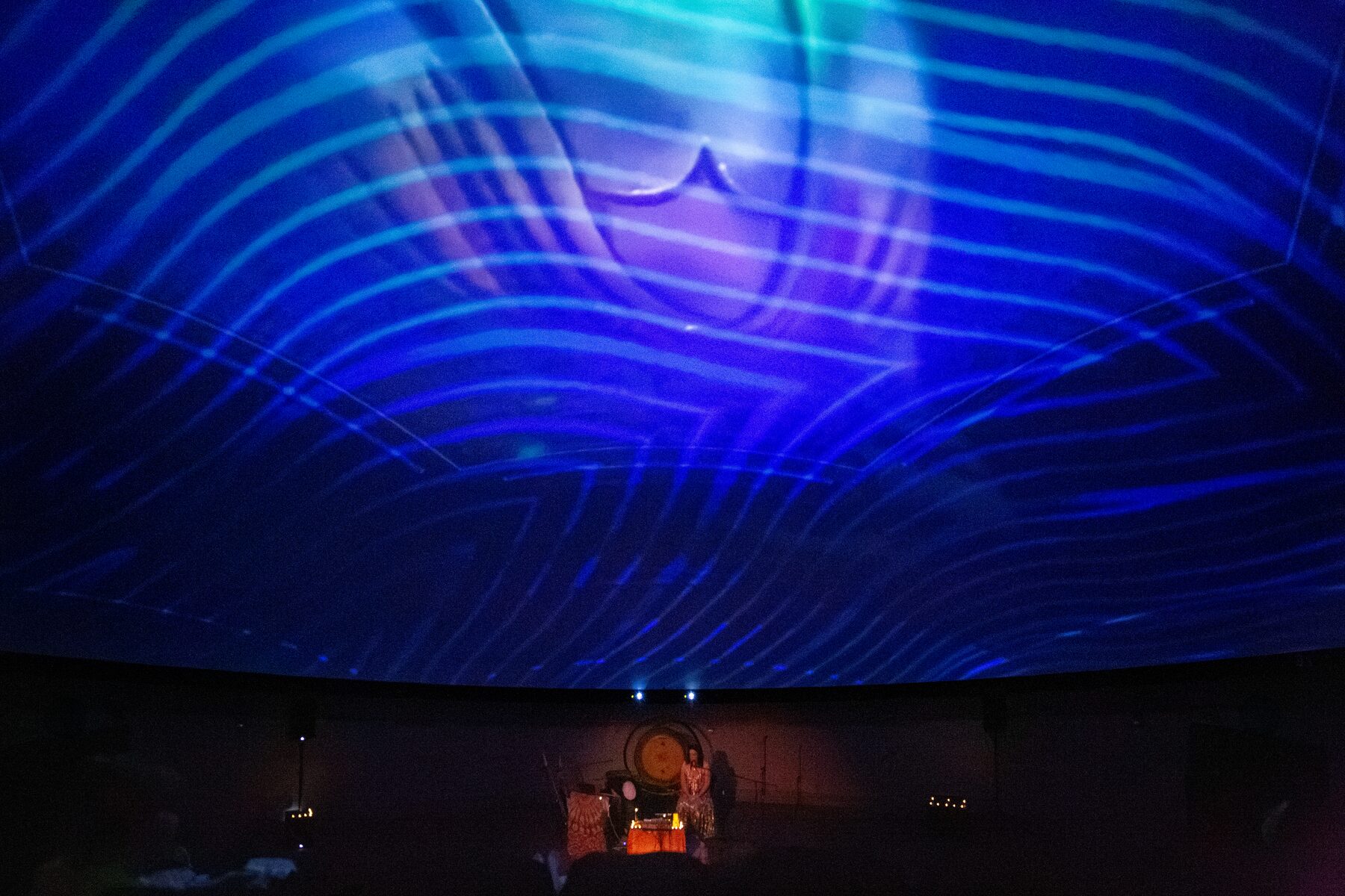 Concentric waves of electric blue ripple outward across the planetarium dome