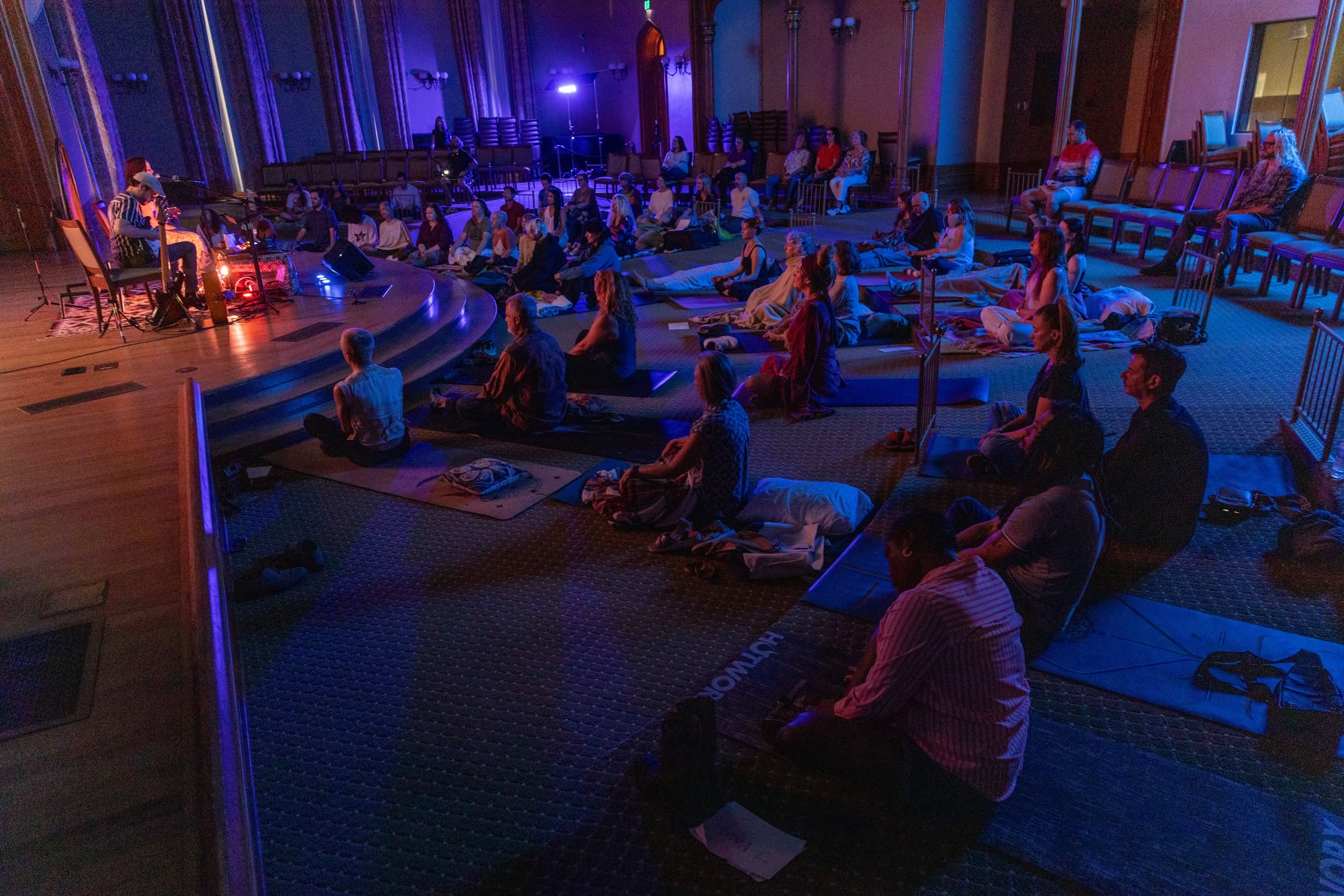 The audience rests on mats across the candlelit chamber as Sariah and Taylor perform